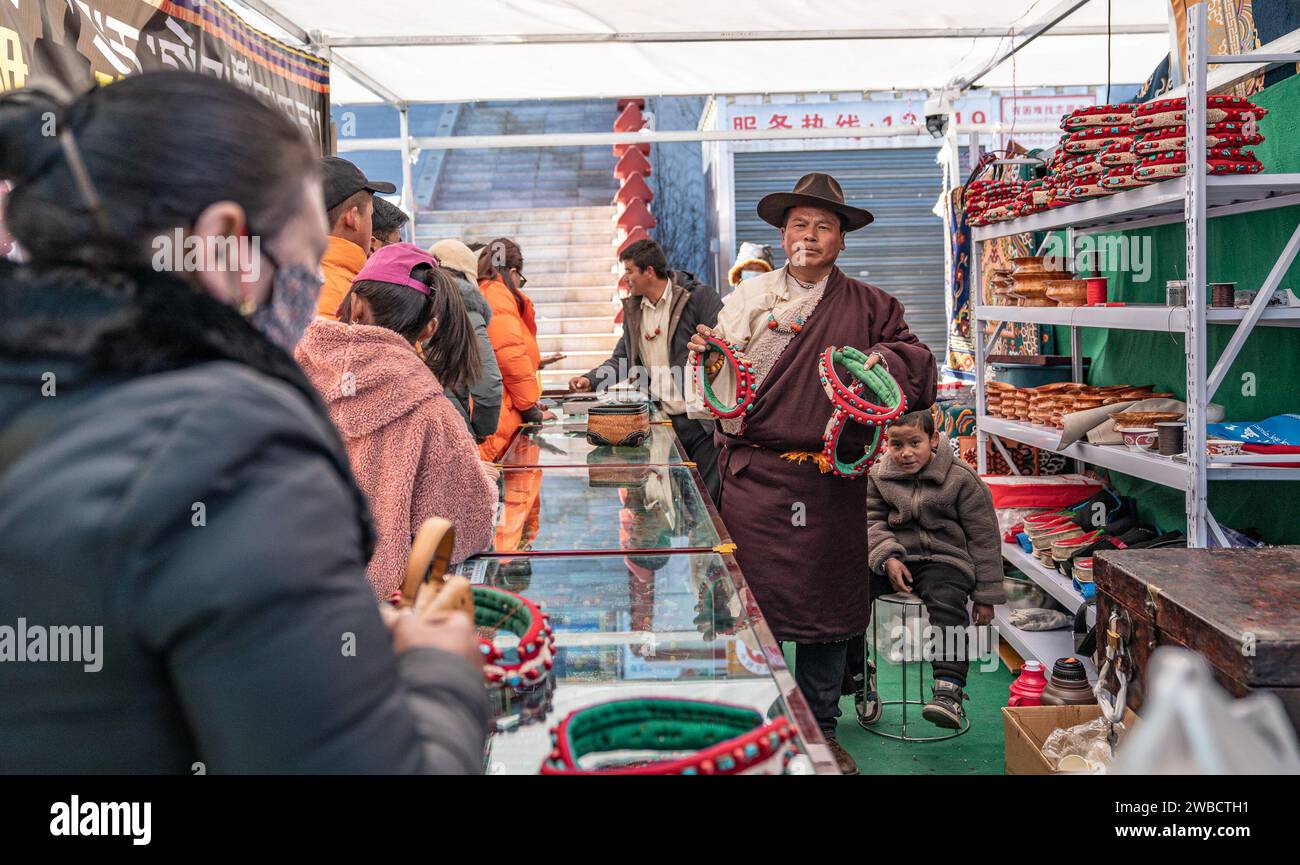 Lhasa, regione autonoma cinese di Xizang. 9 gennaio 2024. Un venditore promuove i copricapo tibetani tradizionali in un mercato a Xigaze, nella regione autonoma di Xizang della Cina sud-occidentale, 9 gennaio 2024. La gente del posto a Xigaze festeggia il Capodanno degli agricoltori il primo giorno del dodicesimo mese del calendario tibetano, che cade il 12 gennaio di quest'anno. Con l'avvicinarsi del festival, le strade e i mercati di Xigaze trasudano un'atmosfera allegra e festosa. Crediti: Tenzin Nyida/Xinhua/Alamy Live News Foto Stock