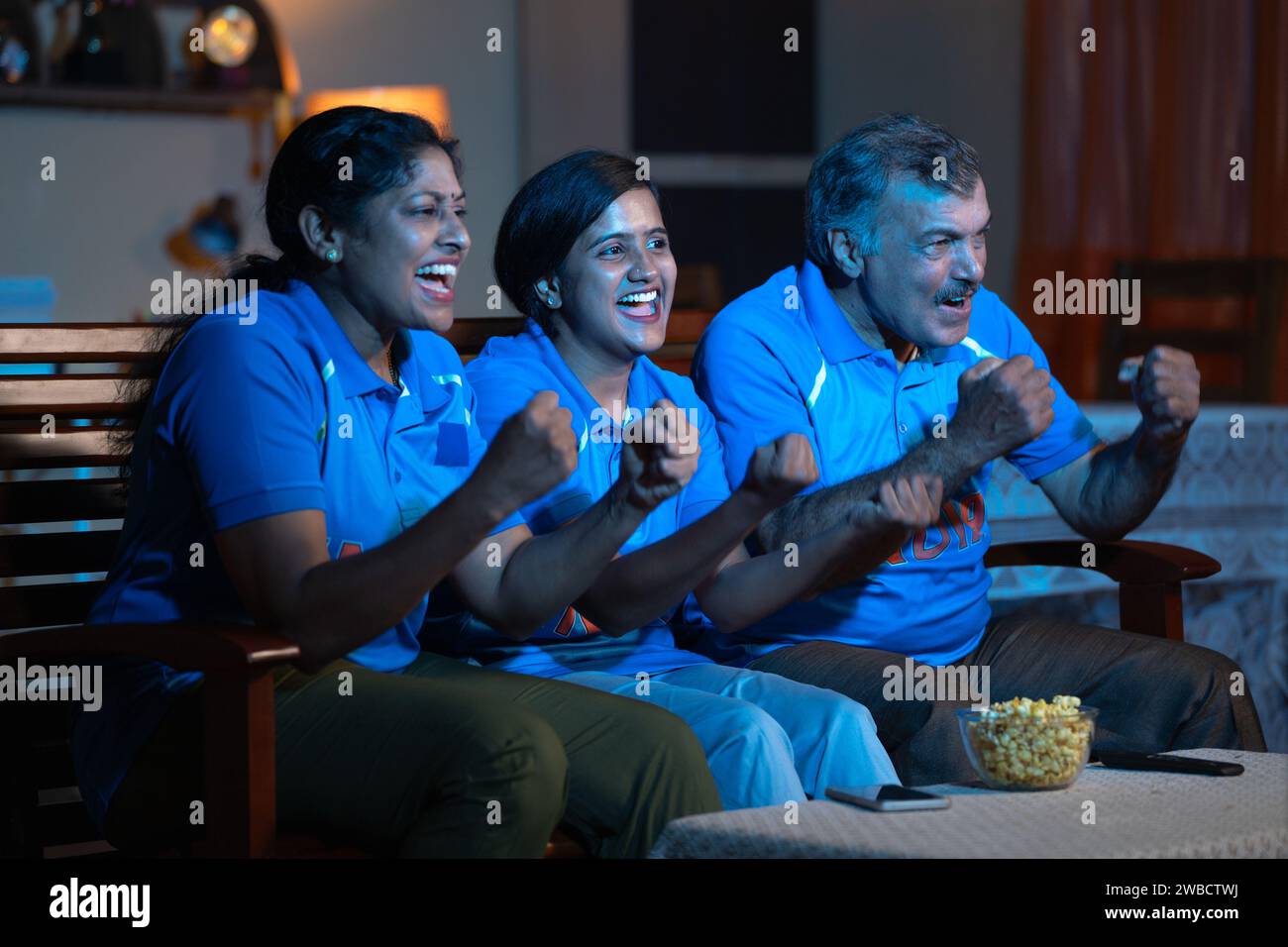 Allegra famiglia che grida come India India mentre guarda una partita di cricket dal vivo in tv o in televisione per incoraggiamento a casa - Concept Entertainment Foto Stock