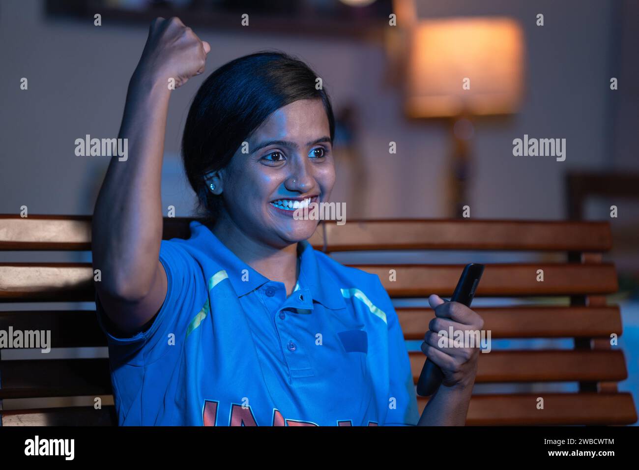 Eccitata ragazza che tira il tifo alla squadra India gridando mentre guardi il cricket a casa in televisione o in tv - concetto di campionato del mondo, sport Foto Stock