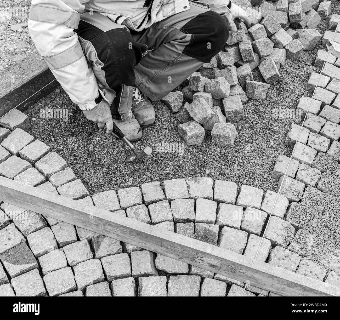 Ripavimentazione del fondo stradale, posa manuale di cubi di porfido sulla strada. Pavimentazione realizzata con cubi di Porfido rosso Trentino, Trentino alto Adige, Italia Foto Stock