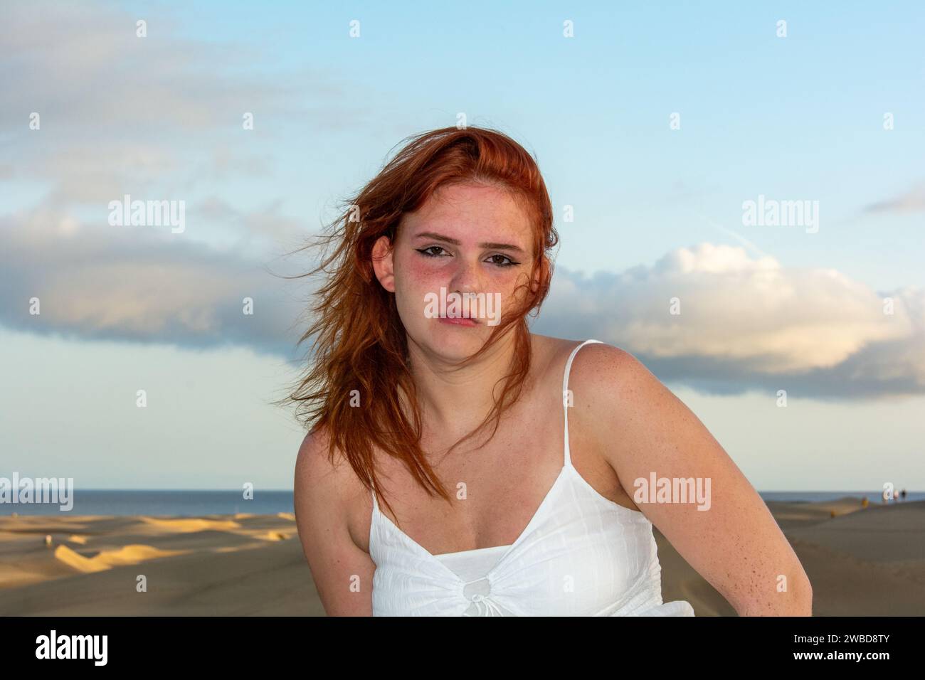 Giovane ragazza con i capelli rossi, in spiaggia d'estate, i suoi capelli sono stregati dal vento Foto Stock