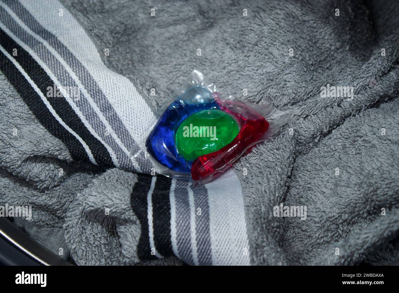 Primo piano di un colorato gel detergente ecologico in capsula sui capi da bucato Foto Stock