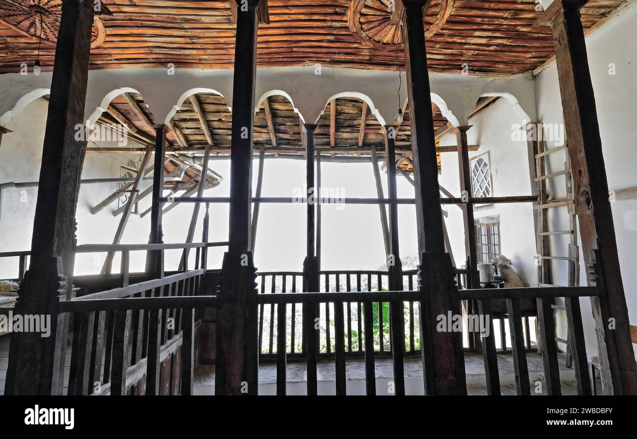 222+ vista dall'interno all'esterno, balcone centrale a sette archi con ringhiera in legno di una casa in stile ottomano nella parte superiore della città vecchia. Gjirokaster-Albania. Foto Stock