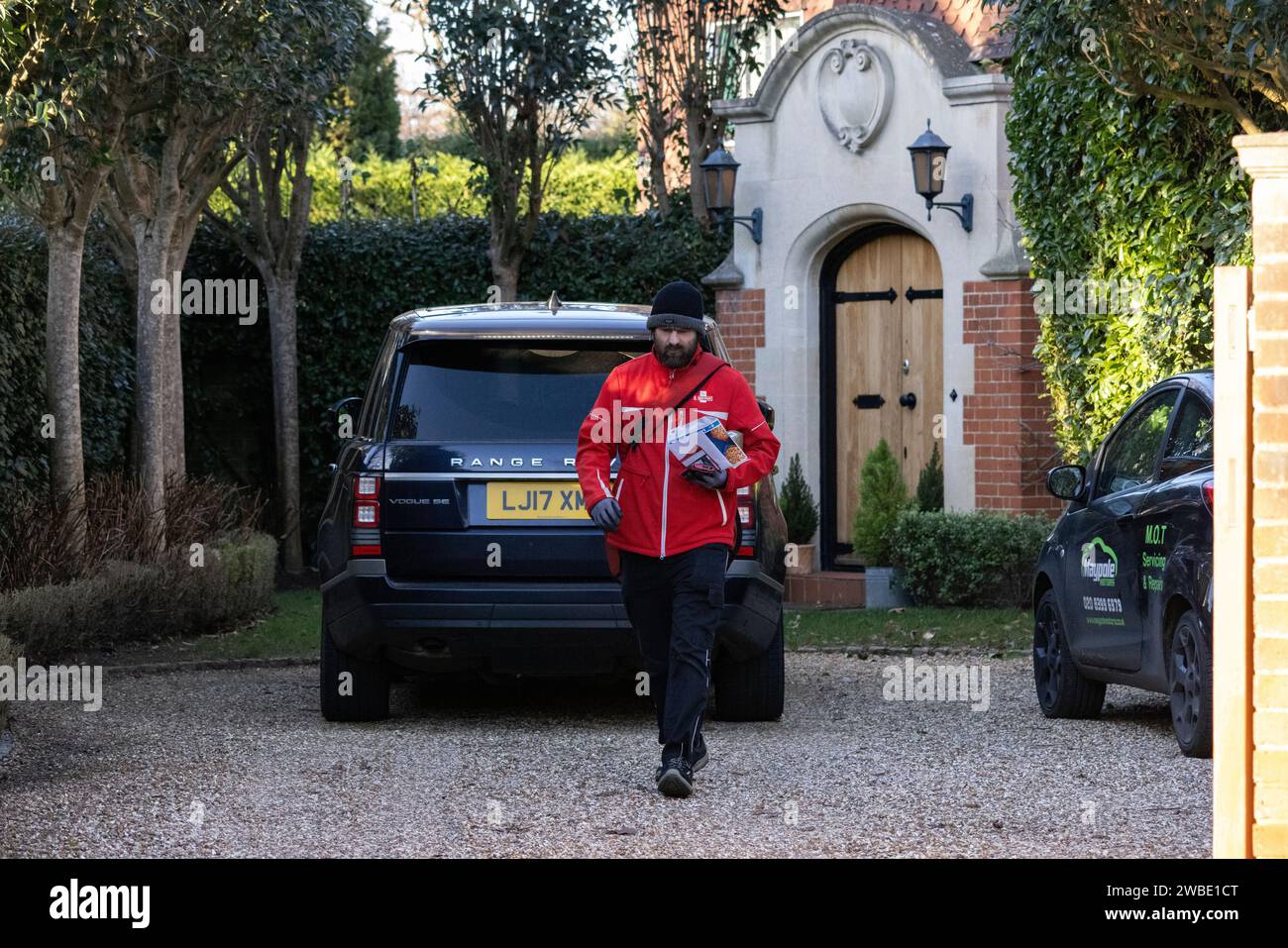 Un postino della Royal mail consegna il suo giro giornaliero all'ex CEO del Royal Mair Group Adam Croziers Property a Weybridge, Surrey, Inghilterra Foto Stock