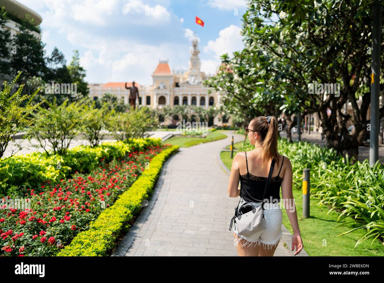 Turista a Saigon. Turismo e viaggi a ho chi Minh City, Vietnam. Donna e statua. Ragazza che cammina nella piazza del giardino del parco urbano di HCMC. Foto Stock