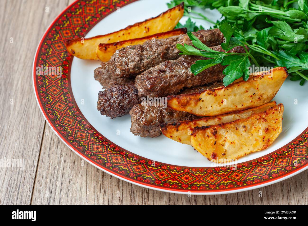 Kebab di Lula su un piatto bianco con bordo rosso con patate al forno e verdure. Kebab Lula di agnello, kebab di manzo lula, kebab di pollo da vicino. Foto Stock