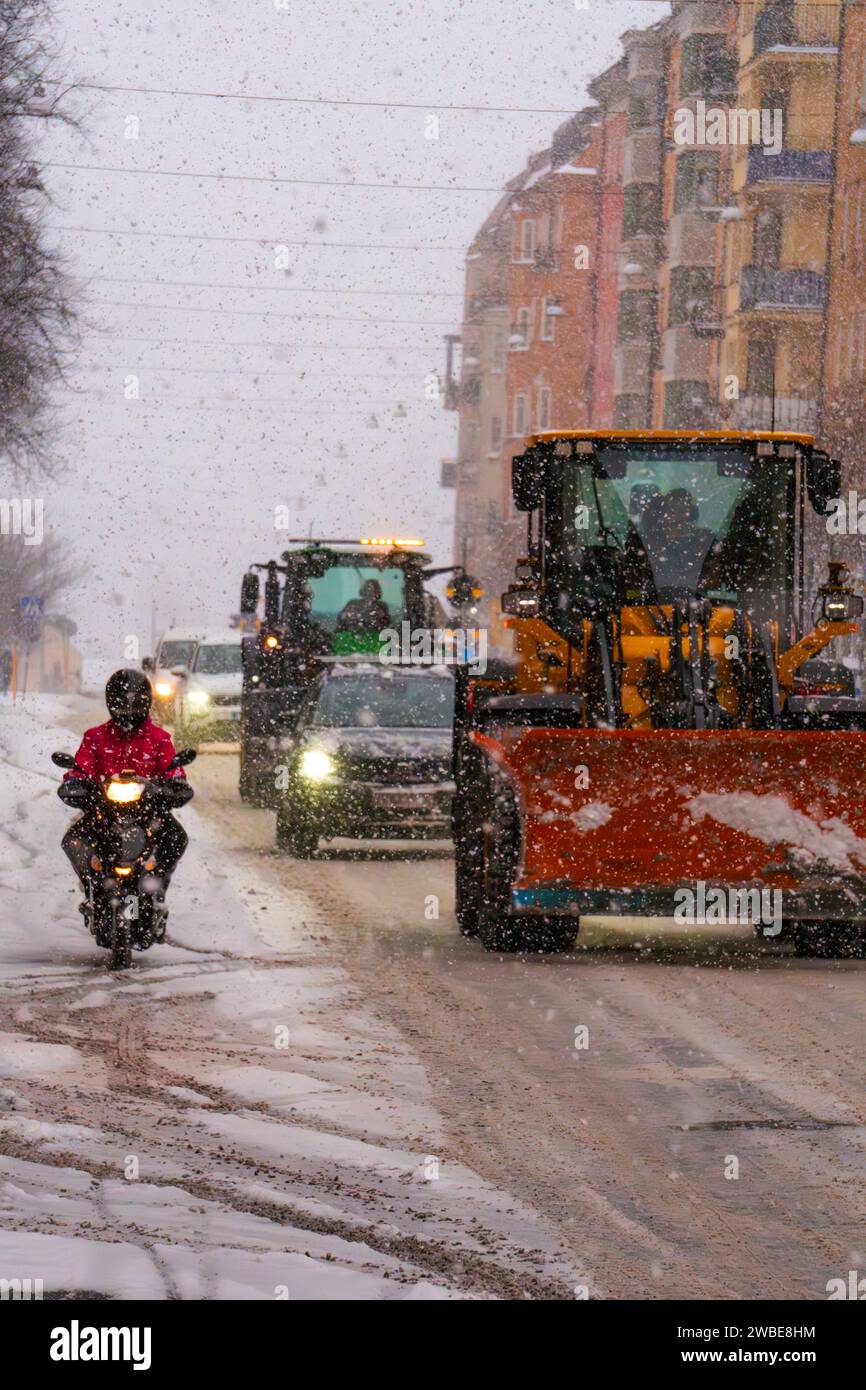 Una persona che lavora per un'azienda di distribuzione di generi alimentari che affronta la tempesta di neve su una motocicletta, con vento forte e temperatura fredda. Gig Economy, Stoccolma Svezia Foto Stock