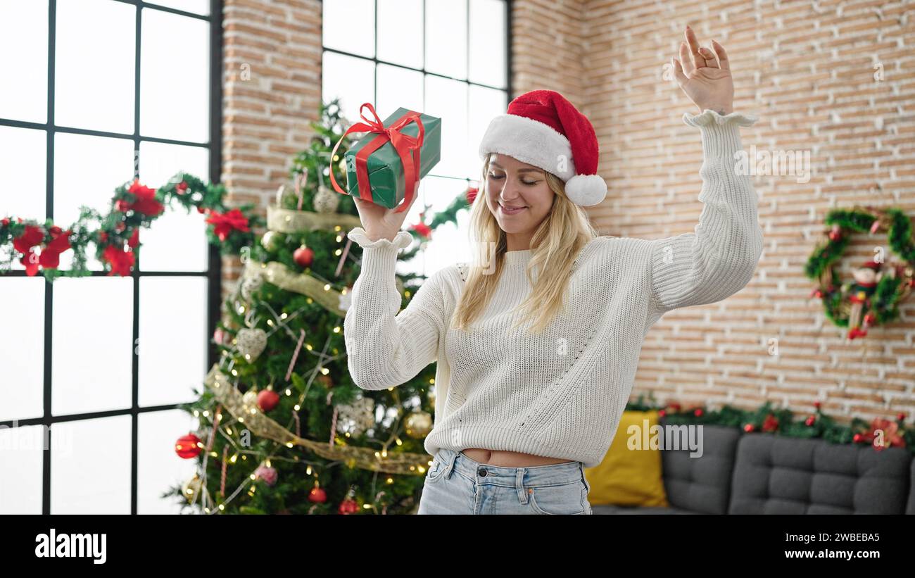 Giovane bionda che tiene un regalo di natale a casa Foto Stock