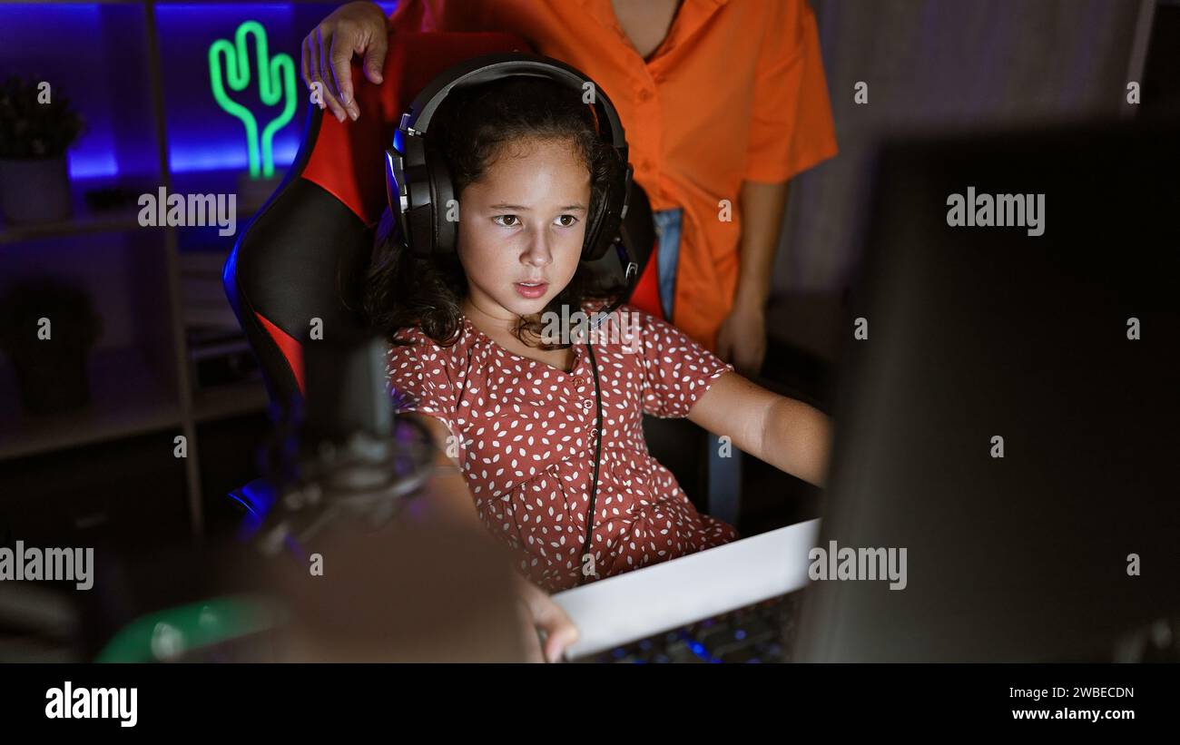 Il duo di gamer madre-figlia, che trasmette in streaming nella loro accogliente sala giochi, è immerso in un mondo virtuale, unito dall'amore, dalla tecnologia e dalla passione condivisa per il vide Foto Stock
