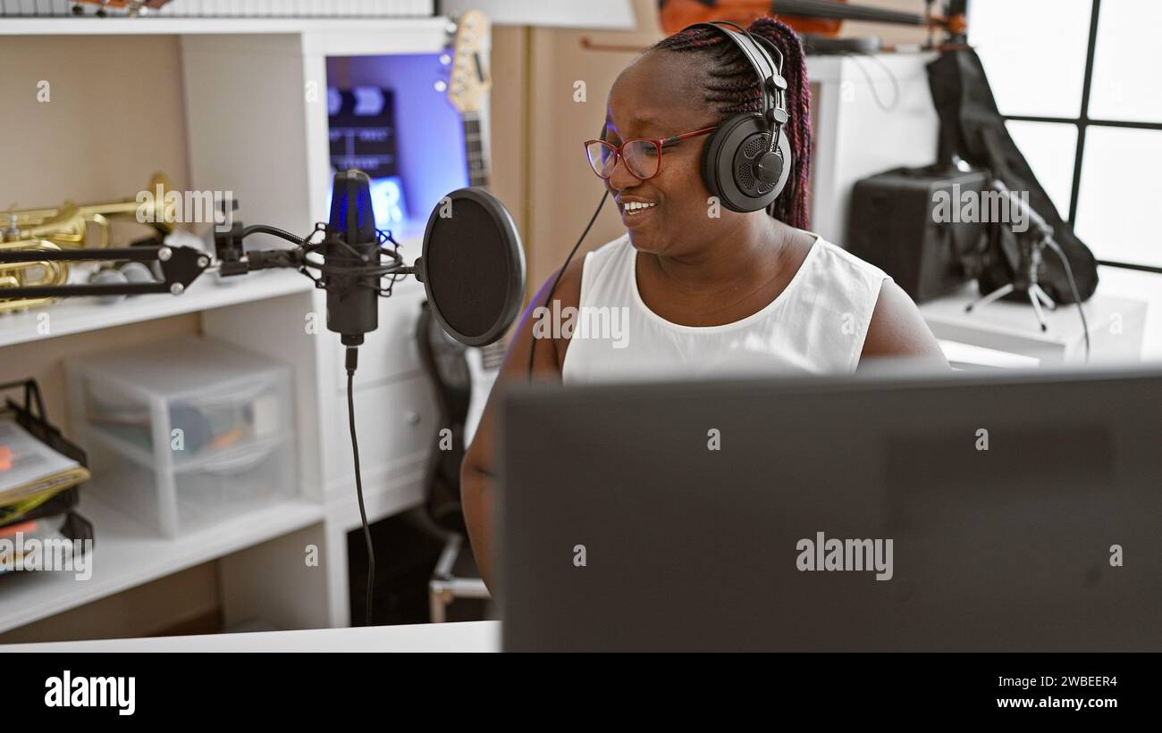 Donna reporter afroamericana che indossa cuffie che presentano notizie allo studio radio Foto Stock