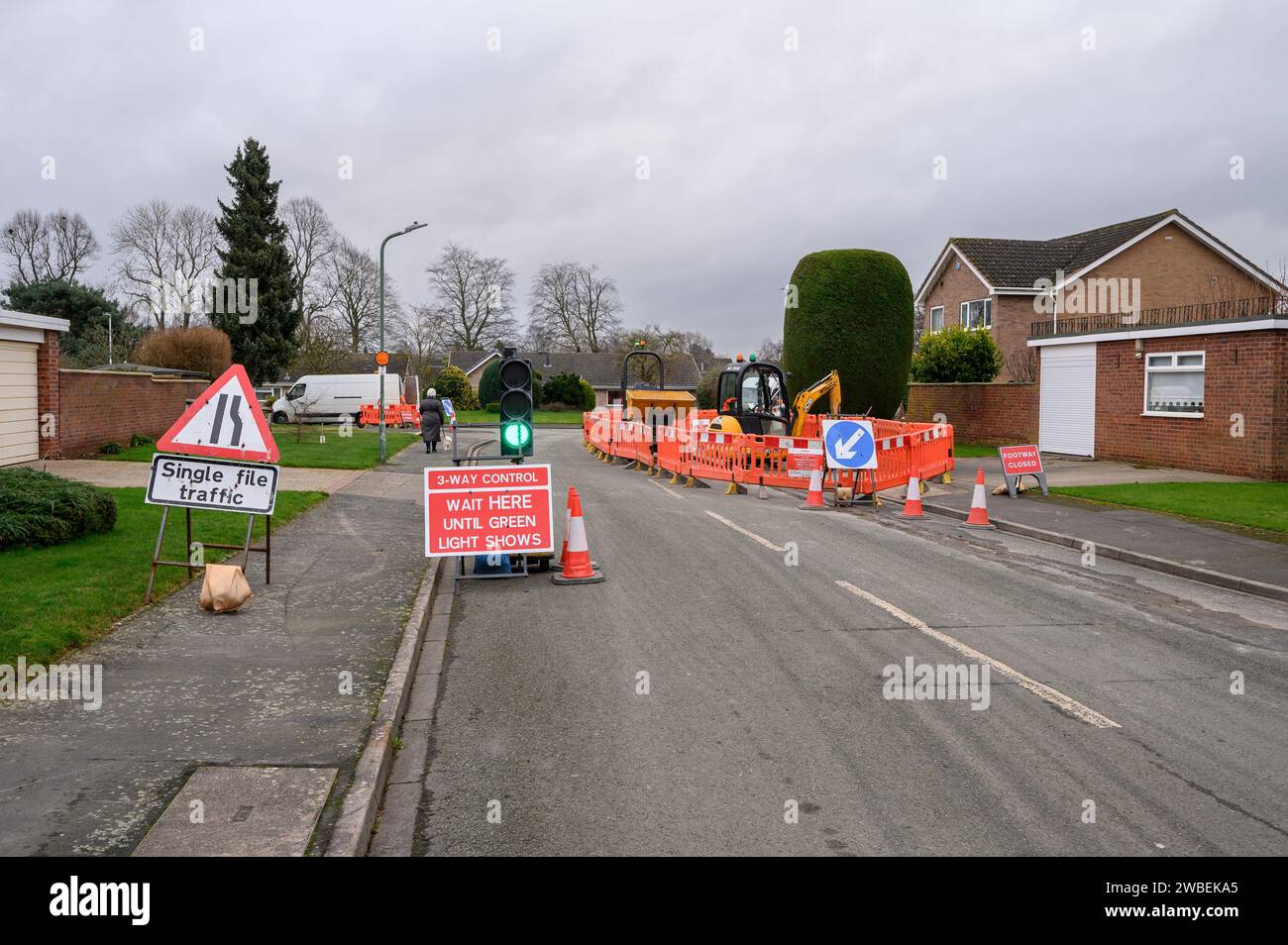 Sentiero chiuso e semaforo che controlla il traffico stradale su una strada urbana con segnali di avvertimento e barriere intorno al sito. Foto Stock