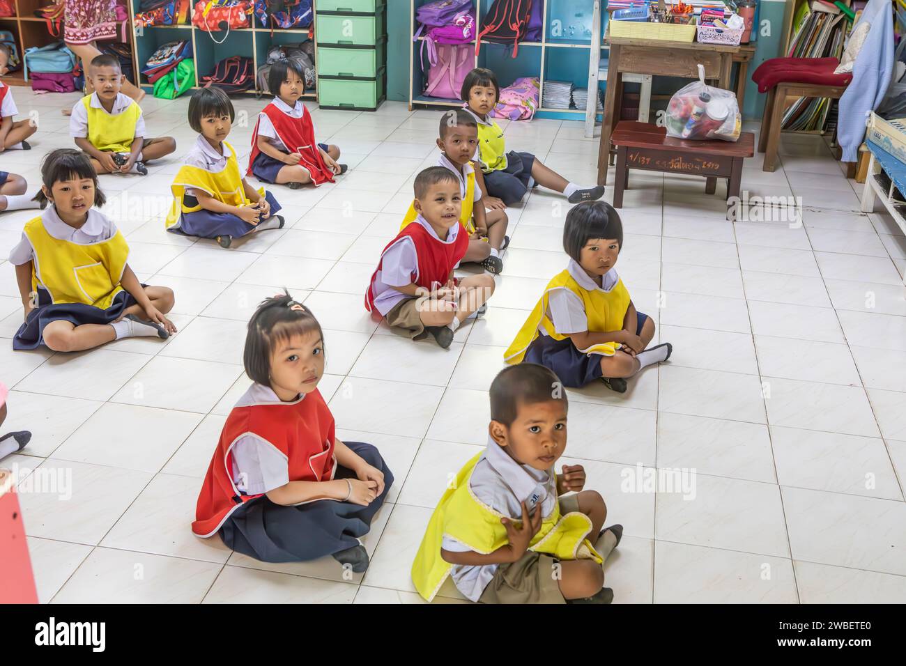 I bambini della scuola thailandese sono seduti al piano della scuola Wat Thai Wiwattanaram, Thailandia. Foto Stock