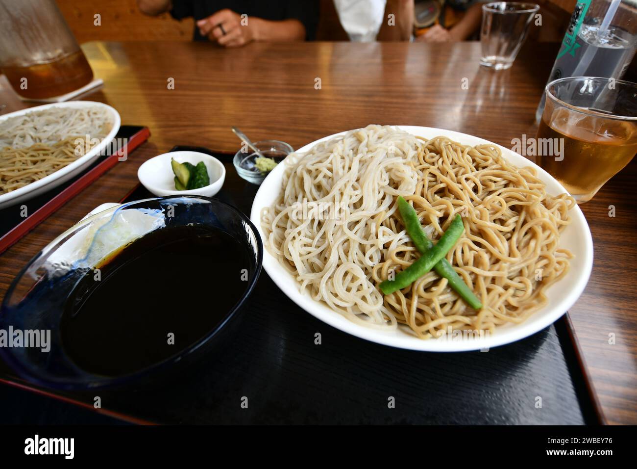 Una persona è seduta a un tavolo, con un paio di ciotole piene di deliziosi noodles davanti a loro Foto Stock