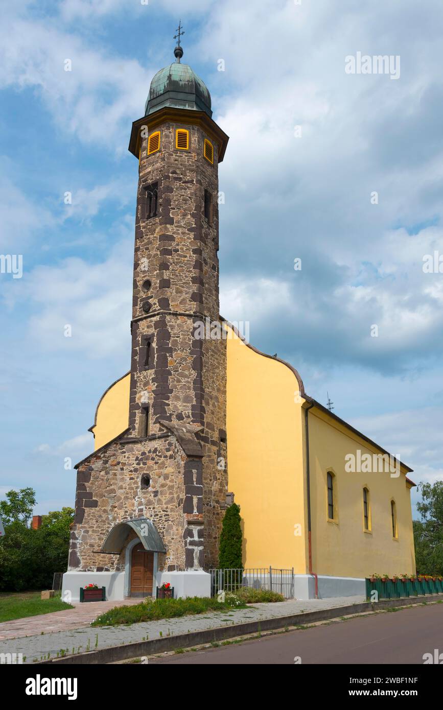 Architettura a torre di chiesa in pietra sotto un cielo nuvoloso accanto a un marciapiede, St. Nicholas Church, Gyoengyoessolymos, Gyoengyoes Matra, Heves, Northern Foto Stock