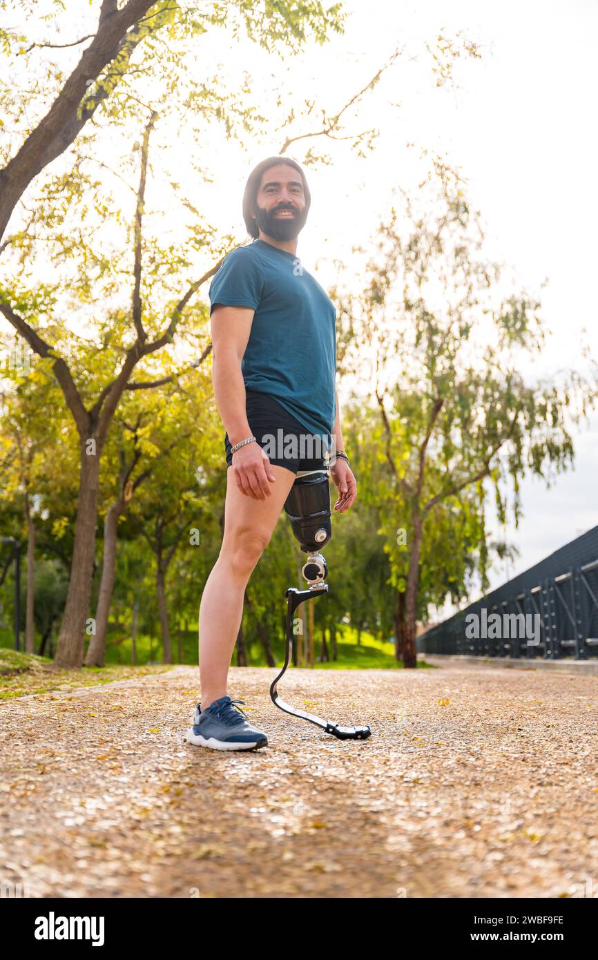 Ritratto verticale di un orgoglioso sportivo con gamba protesica in piedi in un parco Foto Stock