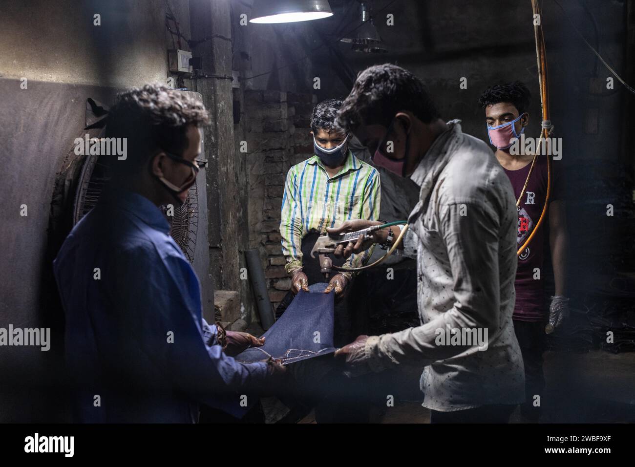Lavoratori che colorano un paio di jeans in una fabbrica tessile, Dacca, Bangladesh Foto Stock