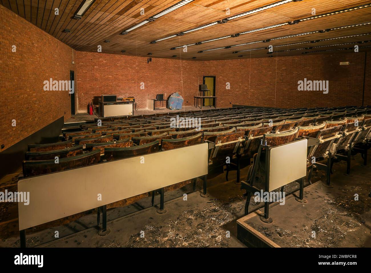 Un teatro di conferenze abbandonato con sedili in legno danneggiati e un modello sferico sul palco, Biotech, università abbandonata, posto perduto Foto Stock