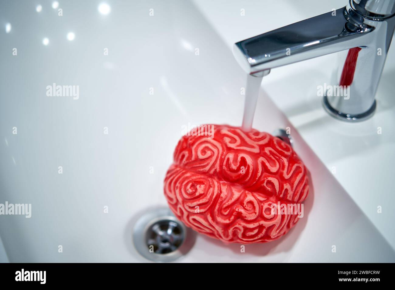 Cervello umano sotto un flusso d'acqua rubinetto, concetto di lavaggio del cervello. Foto Stock