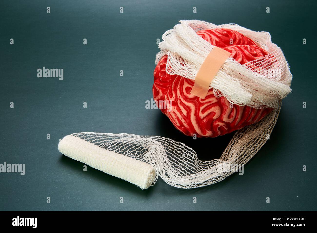 Rappresentazione di un cervello rosso bendato con sfondo scuro, concetto di danno cerebrale. Foto Stock