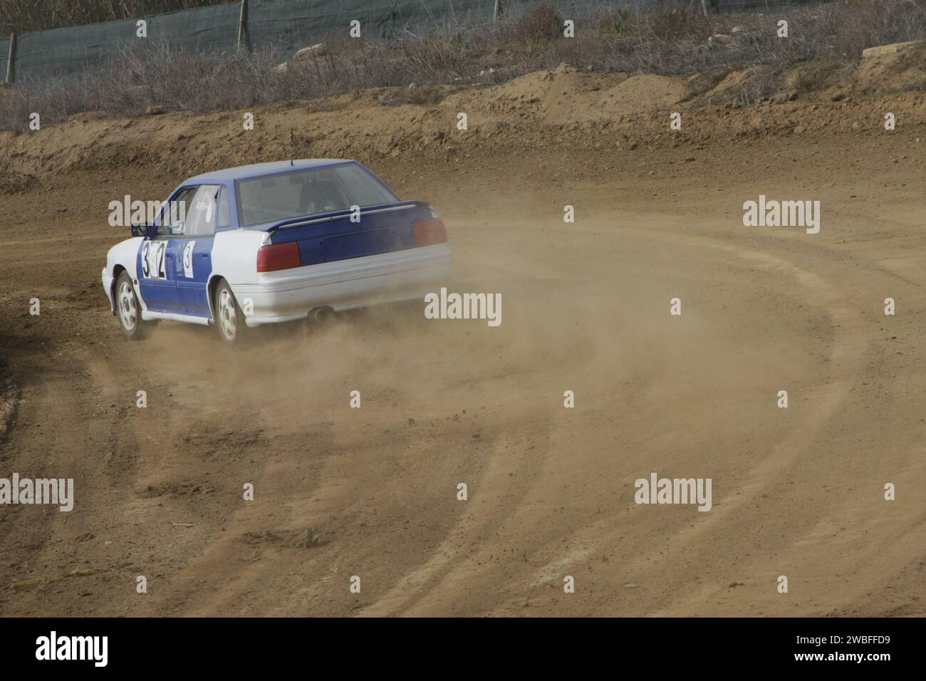 Le auto d'epoca si muovono agevolmente lungo una pista da rally, avvolgendo la polvere in un'accattivante esposizione d'epoca Foto Stock