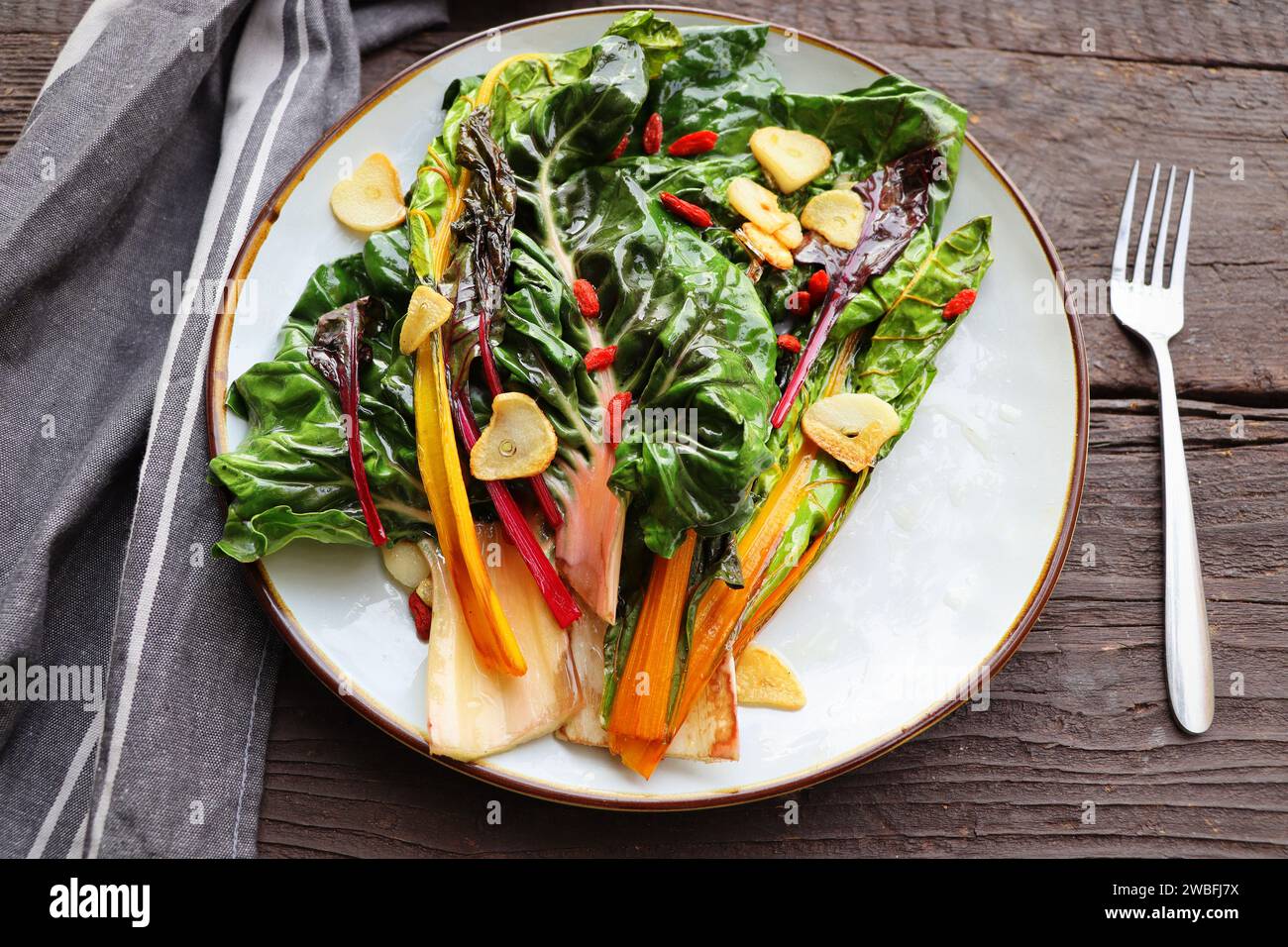 Insalata di bietole svizzera appassita con burro e aglio su tavola rustica. Foto Stock
