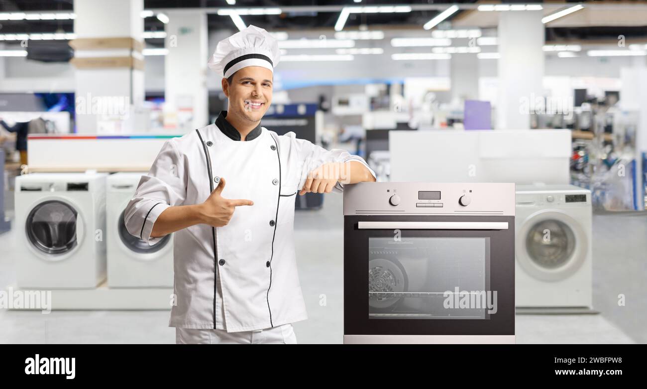 Chef maschio che punta su una stufa all'interno del negozio di elettrodomestici Foto Stock