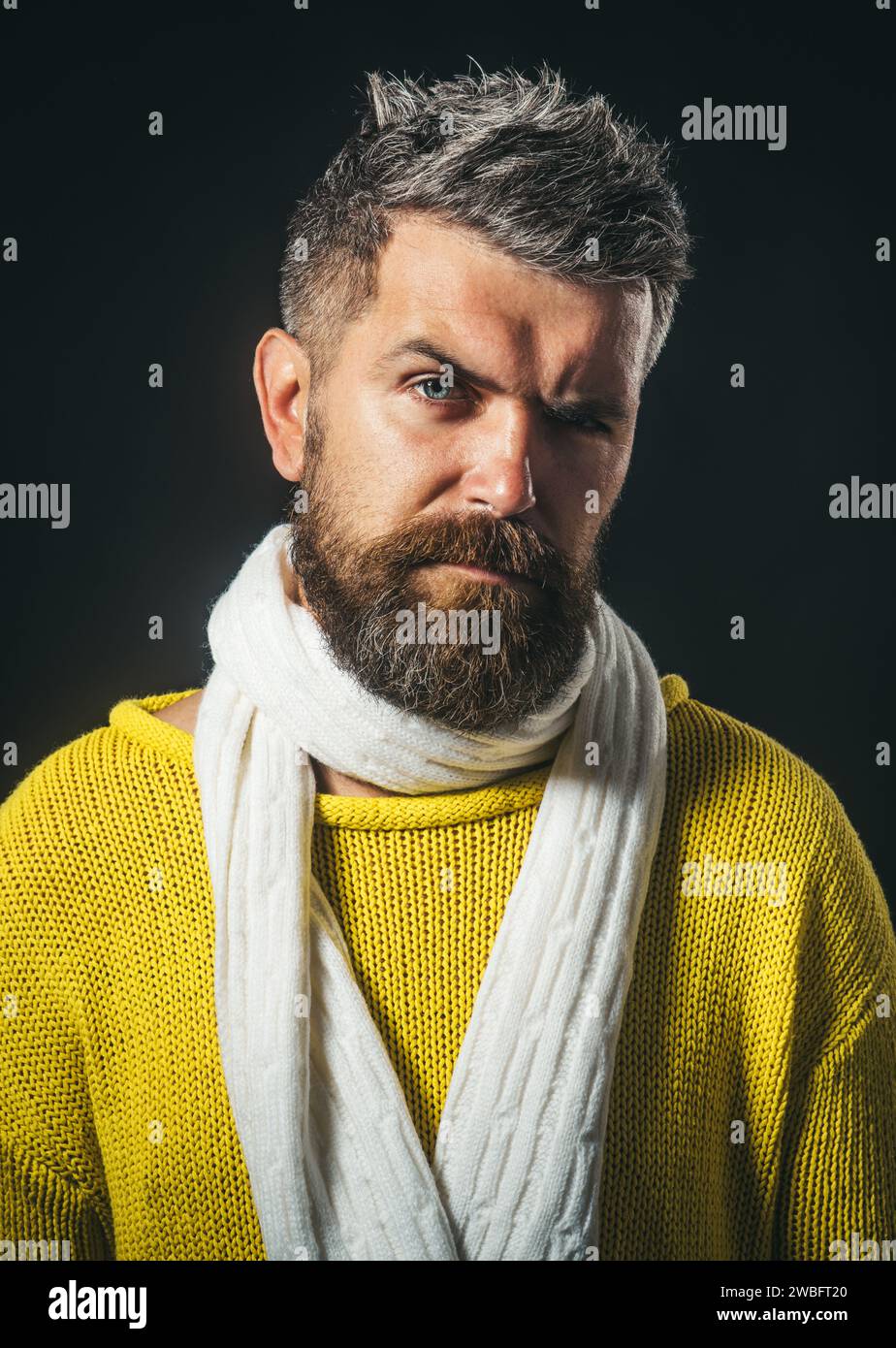 Ritratto in primo piano di un uomo barbuto con elegante acconciatura in maglione giallo e sciarpa bianca. Moda autunno-inverno per gli uomini. Bel modello maschile alla moda Foto Stock