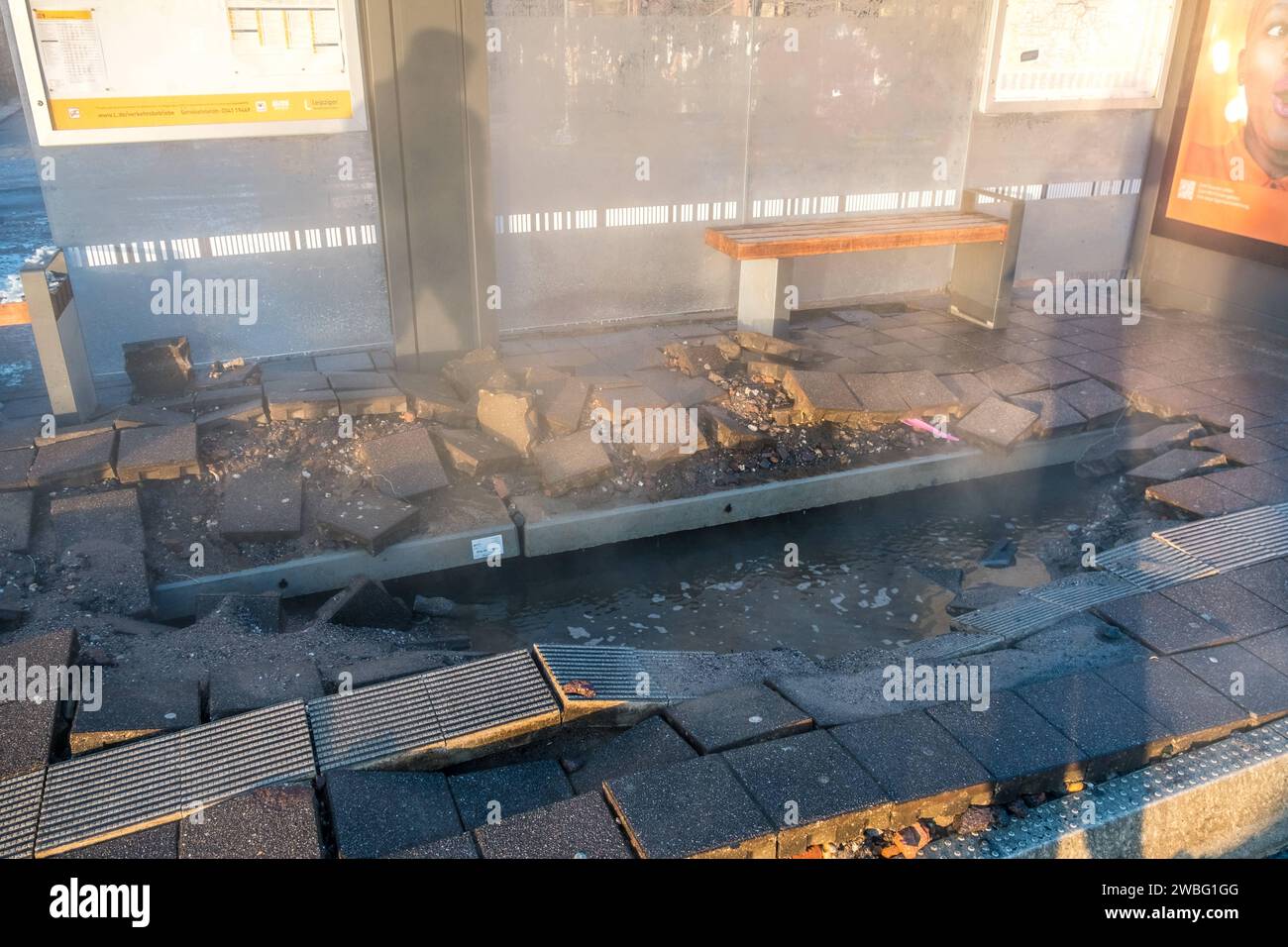 In den frühen Morgenstunden des heutigen Tages ereignete sich an der Haltestelle Hauptbahnhof-Westseite a Lipsia ein Wasserrohrbruch, der vermutlich auf kältebedingte Ursachen zurückzuführen ist. Eine Trinkwasserleitung brach direkt unter dem Wartehäuschen, wodurch das Gehwegpflaster aufbrach und das Wartehäuschen schwer beschädigt wurde. BEI eisigen Temperaturen von -11Â Celsius Floss das Wasser etwa eine Stunde lang die Kurt-Schumacher-Straße hinunter, bis die Leipziger Stadtwerke erfolgreich die Leitung schließen konnten. Die Baustelle des Hotel Astoria wurde ebenfalls a Mitleidenschaft Foto Stock