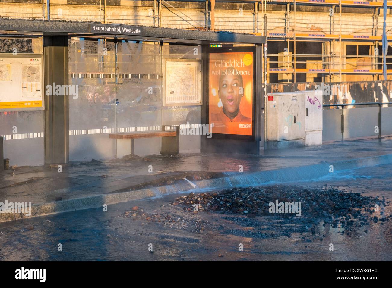 In den frühen Morgenstunden des heutigen Tages ereignete sich an der Haltestelle Hauptbahnhof-Westseite a Lipsia ein Wasserrohrbruch, der vermutlich auf kältebedingte Ursachen zurückzuführen ist. Eine Trinkwasserleitung brach direkt unter dem Wartehäuschen, wodurch das Gehwegpflaster aufbrach und das Wartehäuschen schwer beschädigt wurde. BEI eisigen Temperaturen von -11Â Celsius Floss das Wasser etwa eine Stunde lang die Kurt-Schumacher-Straße hinunter, bis die Leipziger Stadtwerke erfolgreich die Leitung schließen konnten. Die Baustelle des Hotel Astoria wurde ebenfalls a Mitleidenschaft Foto Stock