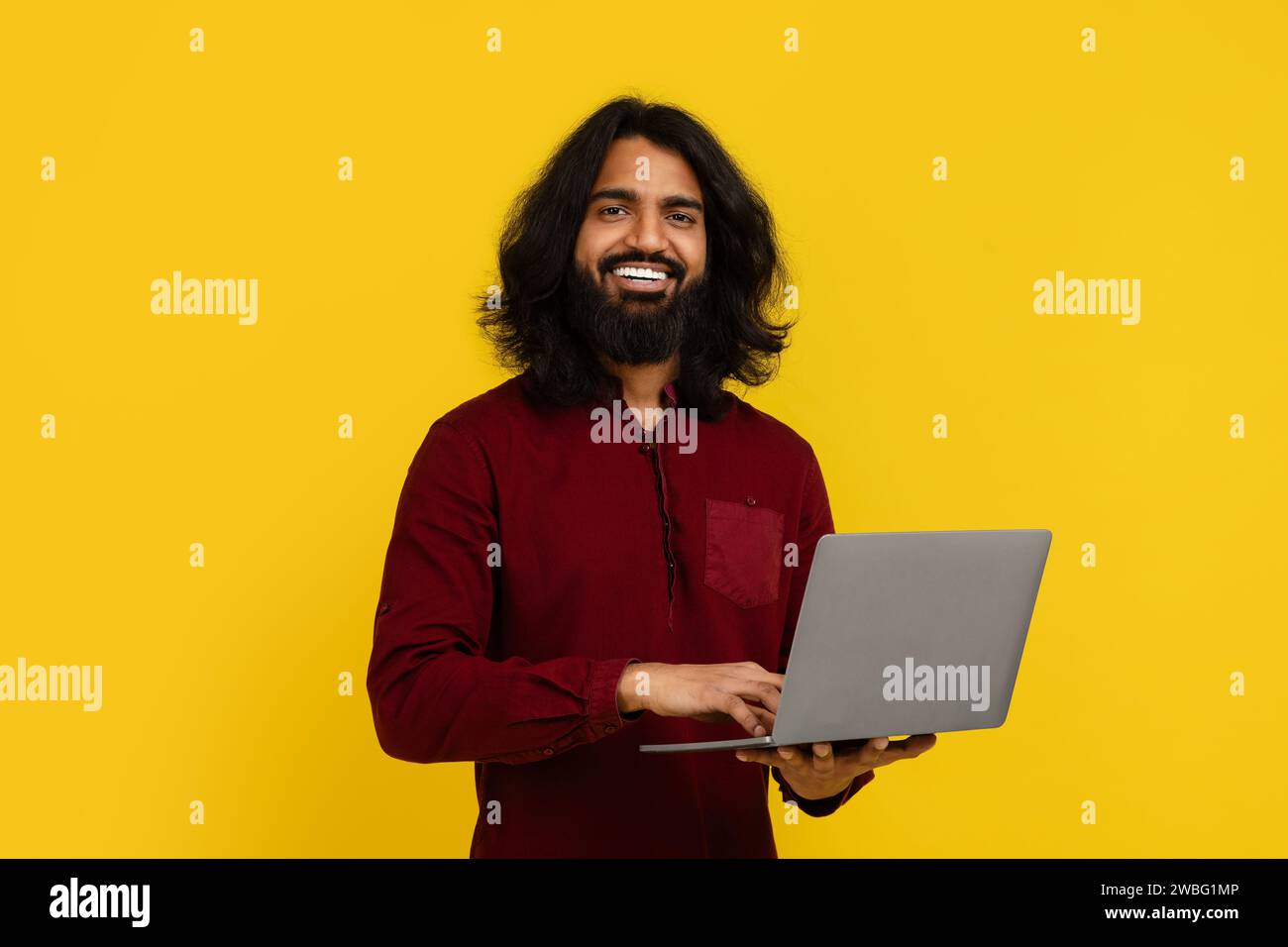 Allegro giovane studente indiano che usa un computer portatile Foto Stock