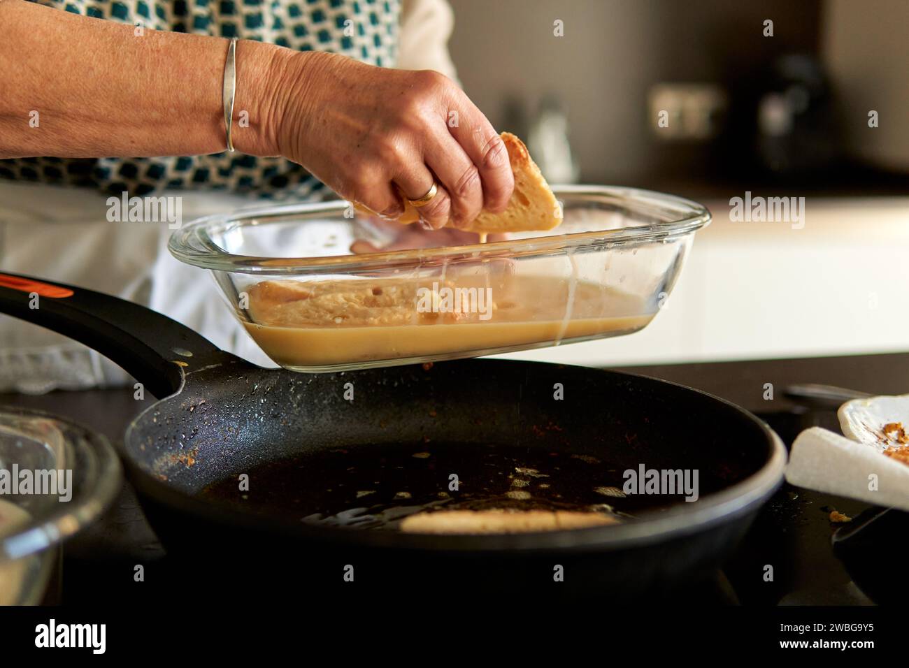 Primo piano delle mani di una nonna che friggono torrija spagnole Foto Stock