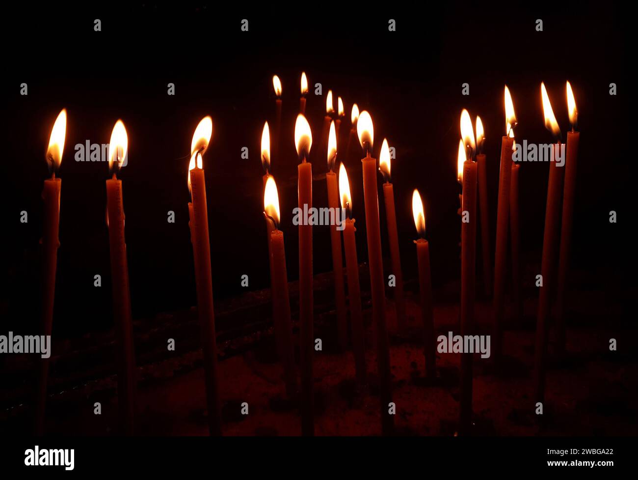 Un gruppo di candele brucia al buio Foto Stock