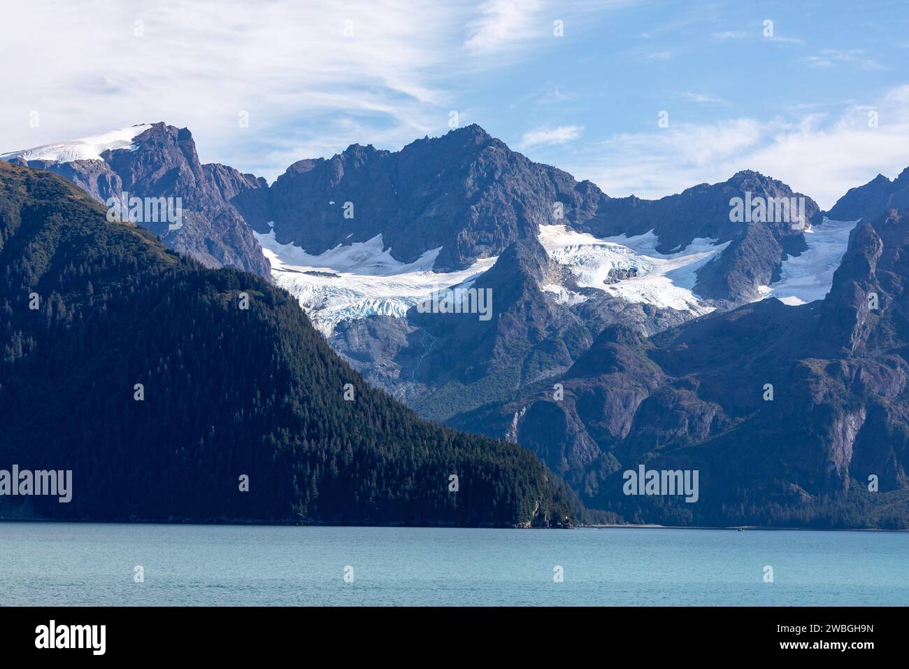 Ghiacciai e picchi frastagliati si innalzano sopra le calme acque blu dell'oceano in una natura incontaminata dell'Alaska Foto Stock