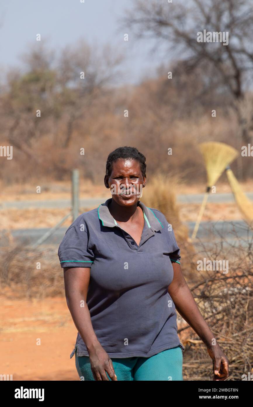 ritratto di una donna africana che cammina vicino all'autostrada, vita del villaggio, sta vendendo scope per strada Foto Stock