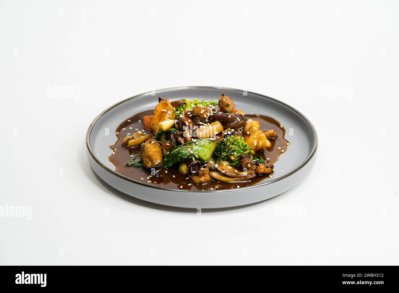 Piatto asiatico fritto con salsa agrodolce, aglio e verdure su un piatto, vista laterale Foto Stock