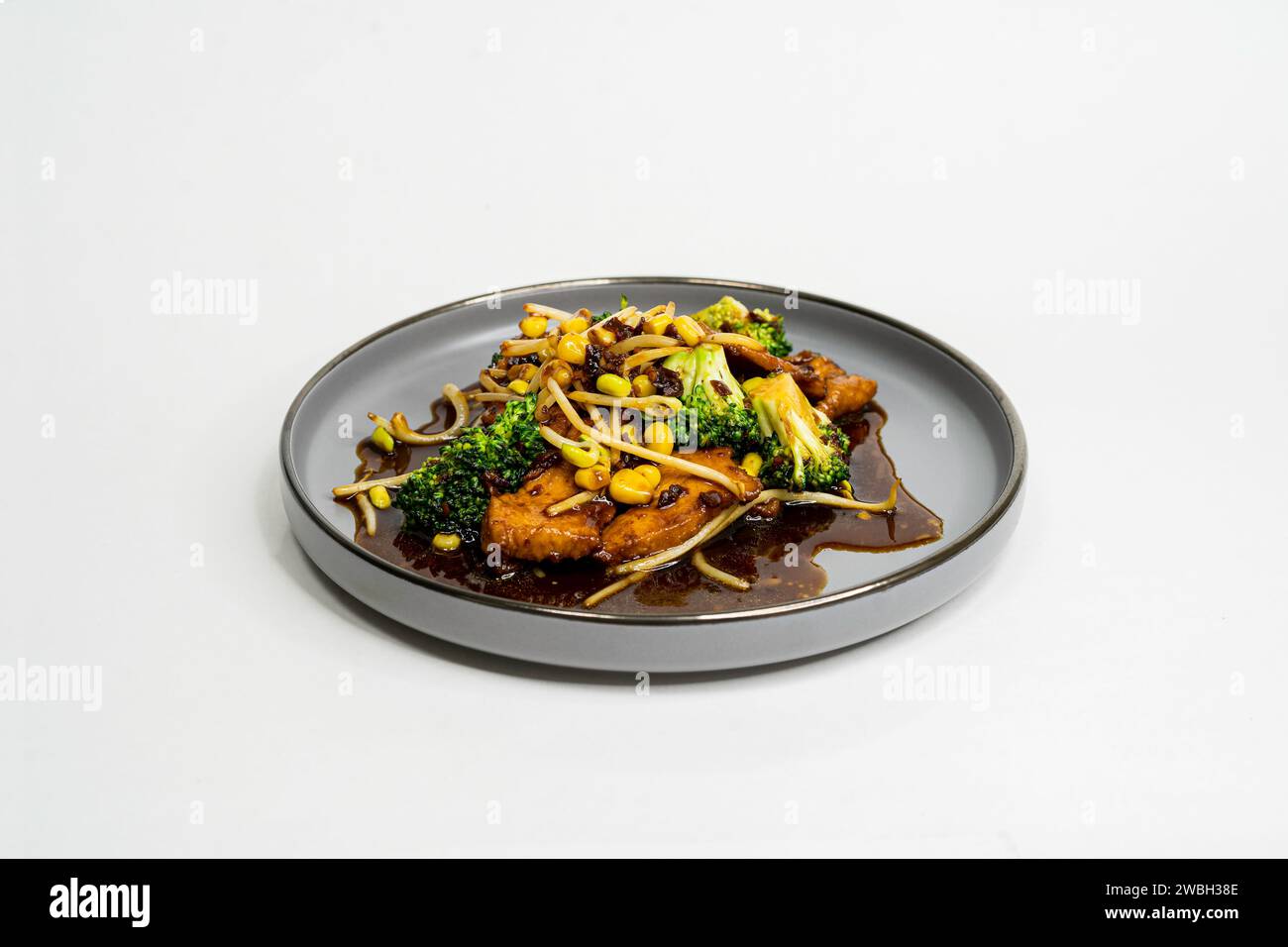 Piatto asiatico fritto con salsa agrodolce, aglio e verdure su un piatto, vista laterale Foto Stock