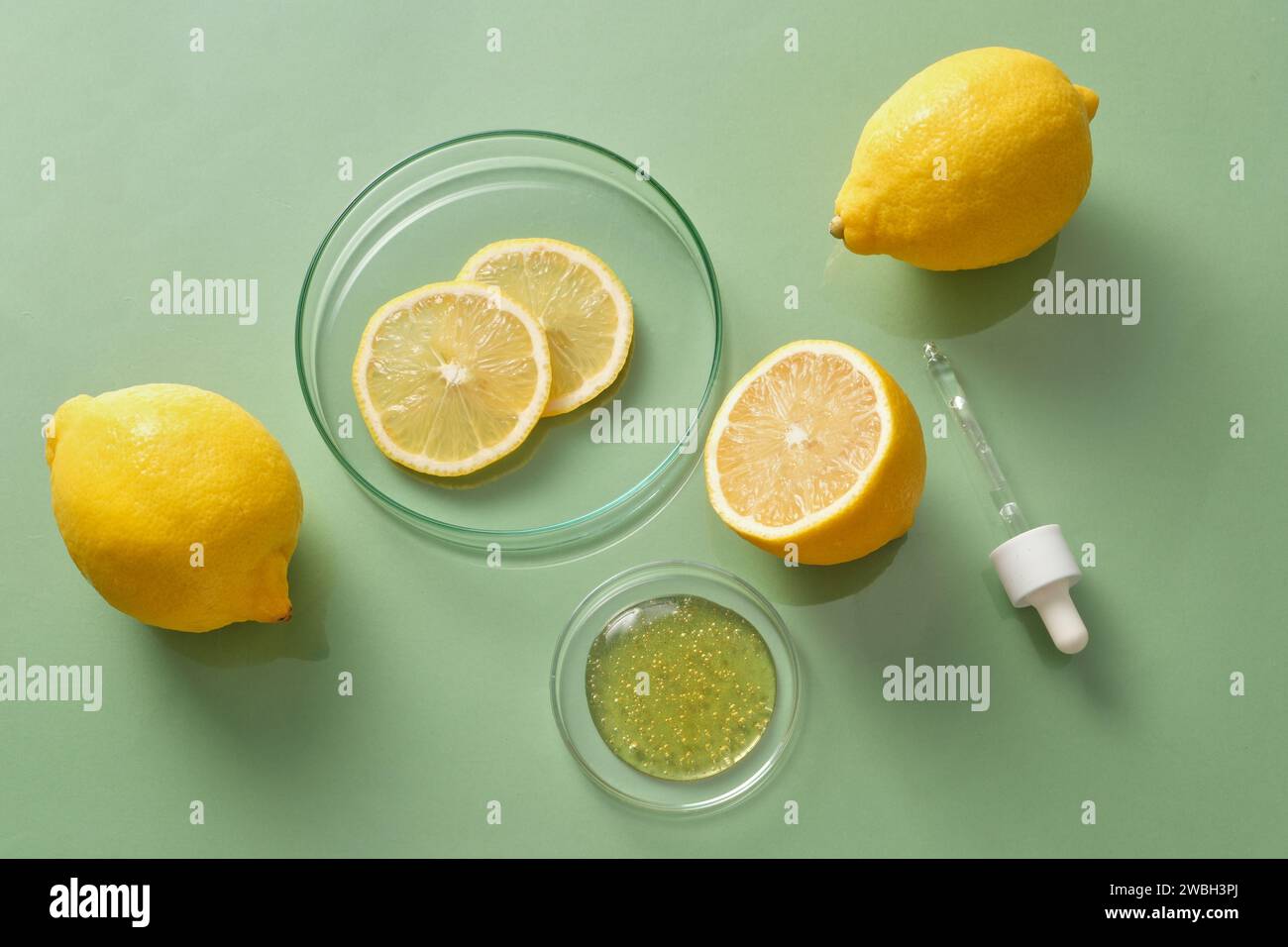 Vista dall'alto delle fette di limone fresco e limone decorate su uno sfondo verde con l'essenza del contenitore di petri e contagocce. Concetto di cosmetici naturali W Foto Stock