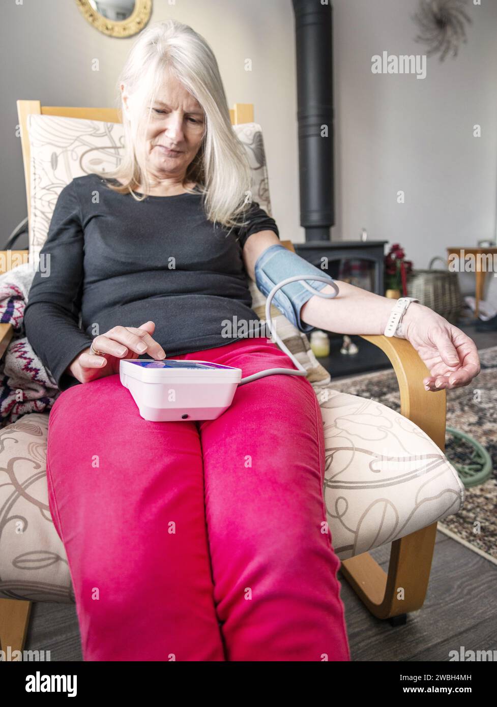Una donna di mezza età che controlla la pressione sanguigna nella sua casa a Worcestershire, Inghilterra, Regno Unito. Foto Stock