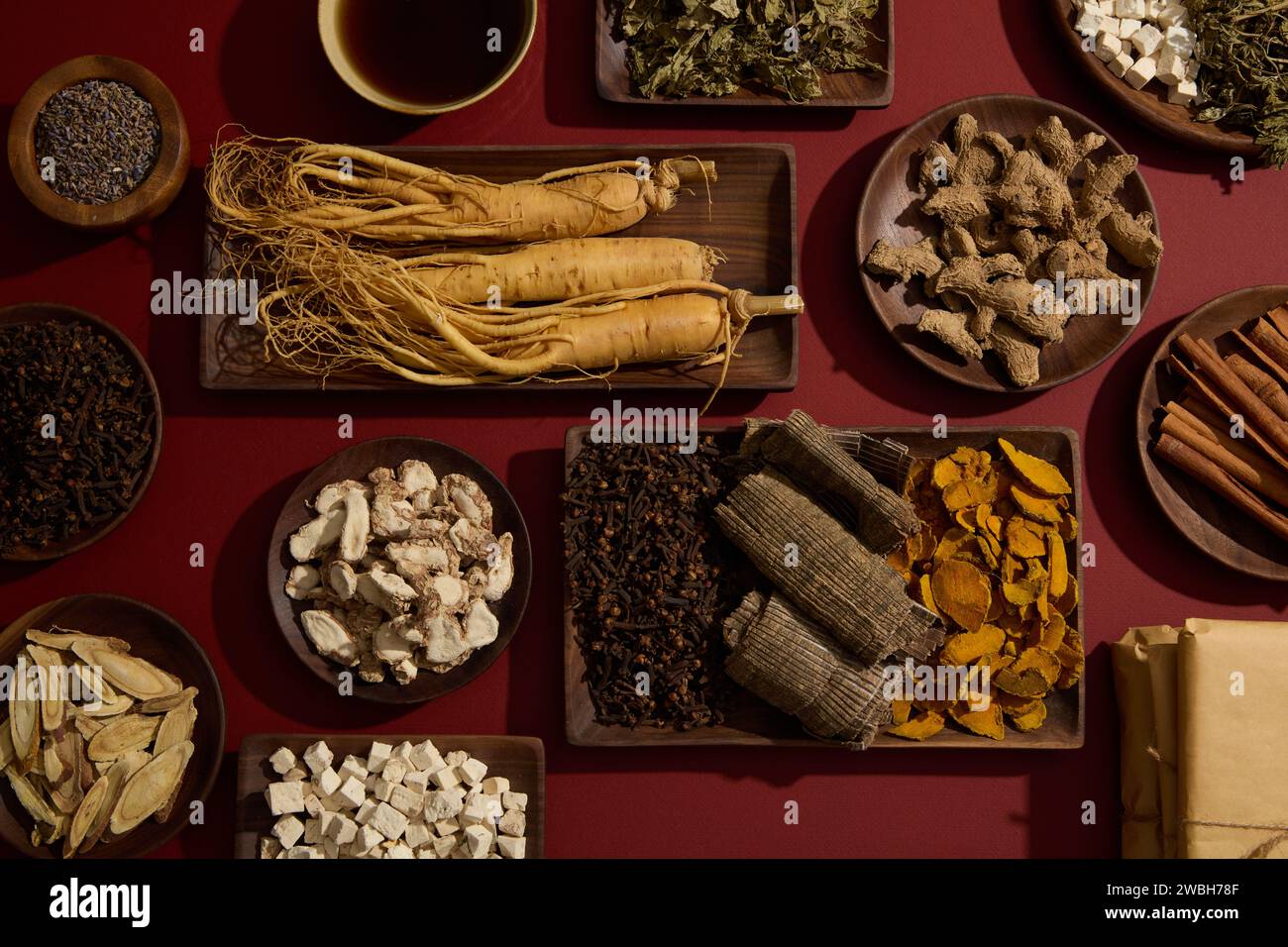 Lo sfondo rosso presentava molti tipi di erboristeria tradizionali collocati su piatti di legno. Viene visualizzata una vaschetta tonica. Per la pubblicità di farmaci con Foto Stock