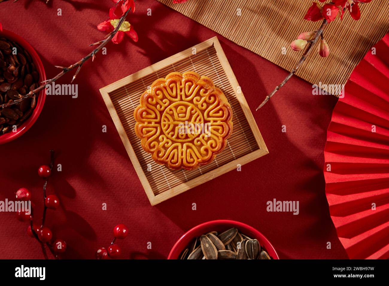 Vassoio di legno a forma quadrata contenente una torta lunare. In mostra ciotole rosse di semi di girasole e semi di melone. La gente di solito guarda la luna piena in Foto Stock