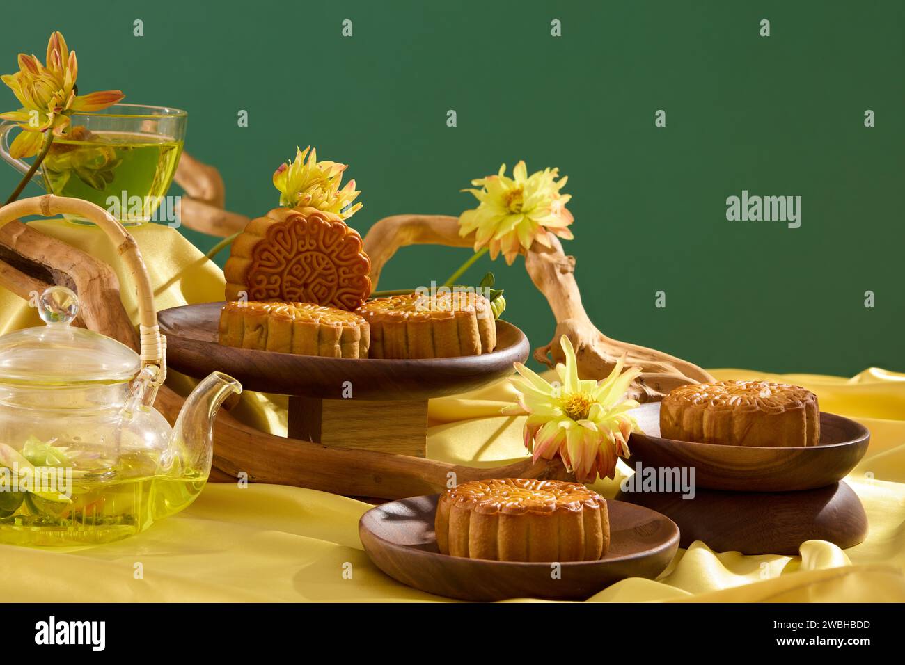 Tradizionale festa di festa dell'Asia orientale con torte di luna al forno su piatti di legno e un set di tè. Rami d'albero e decorazioni di fiori freschi Foto Stock