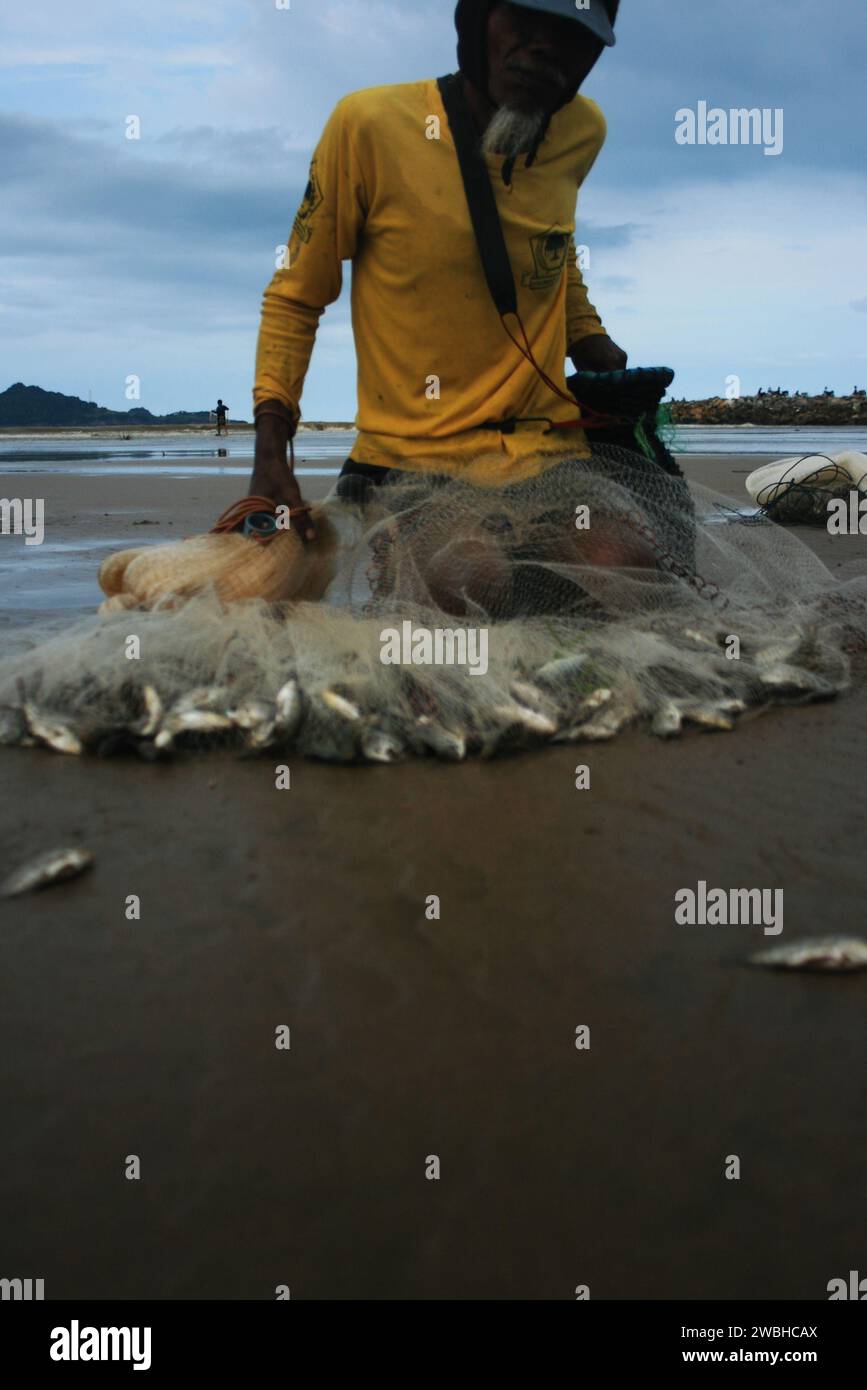 Il pescatore sulla costa del Pacitan raccoglie il pesce nelle reti Foto Stock