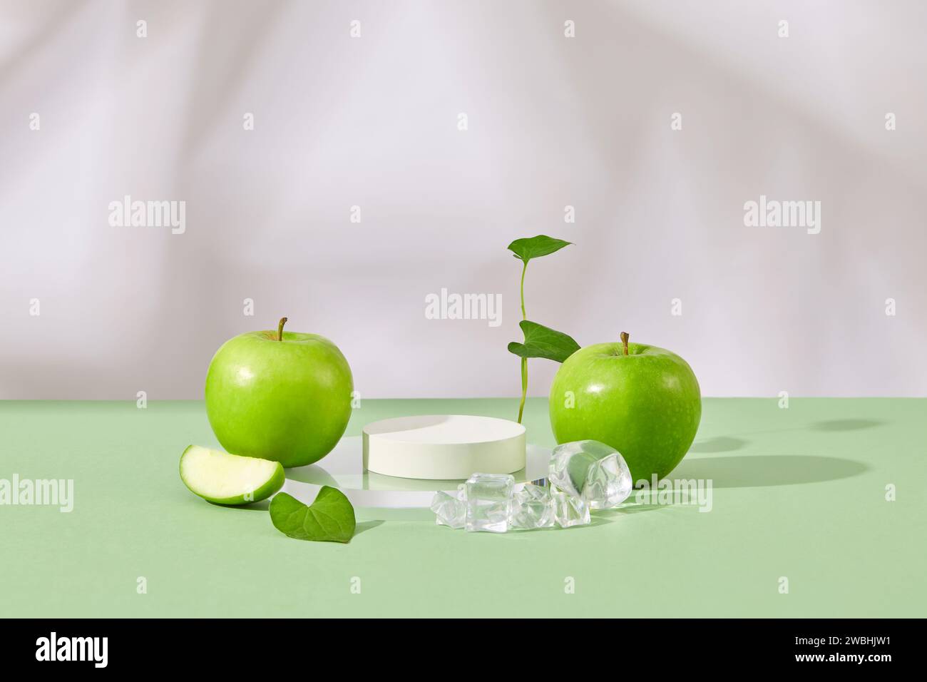 Podio vuoto di colore bianco disposto con ghiaccio e mele verdi fresche. Mockup minimalista per podio o vetrina con Green Apple (Malus domest Foto Stock