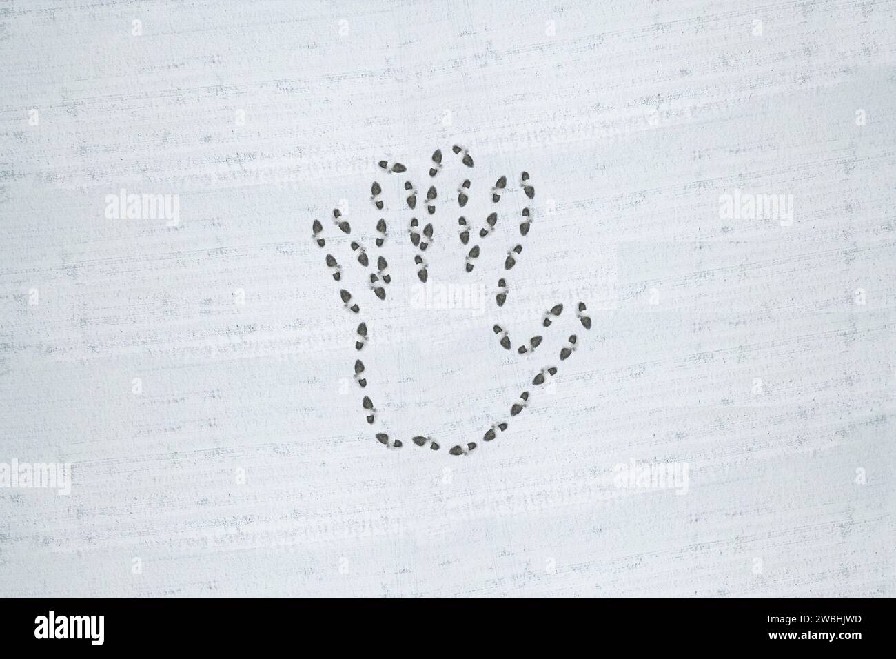 Simbolo della mano impresso sulla neve con impronte. Foto Stock