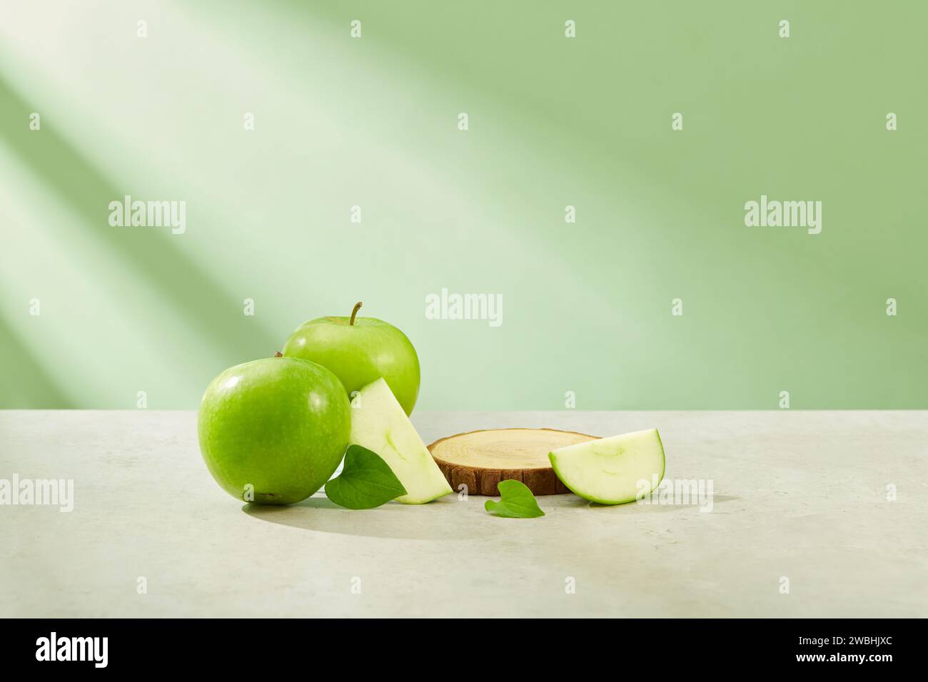 Concetto di frutta sana con podio a forma rotonda disposto sul piatto con mela verde circondata. Spazio libero per esporre prodotti di bellezza naturale extra Foto Stock