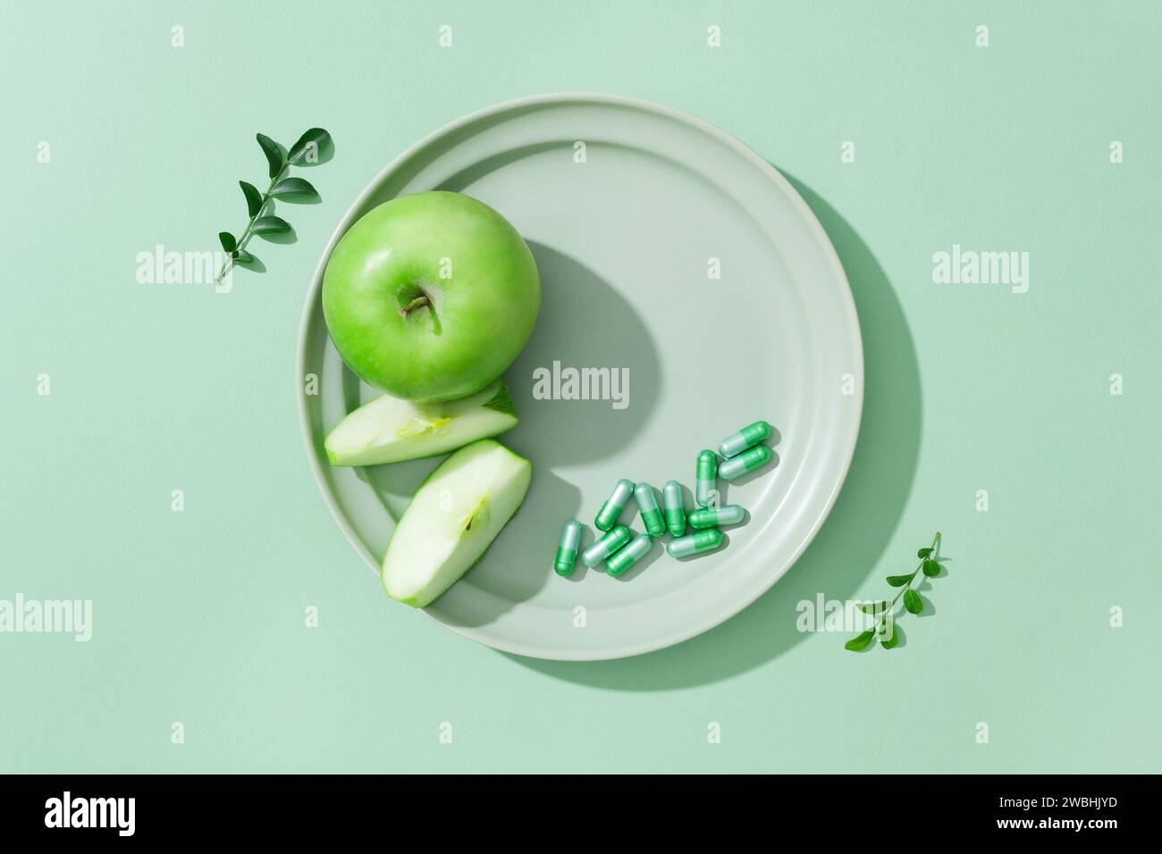 Le fette di mela verde e una manciata di capsule sono esposte su un piatto di ceramica. Spianatura piatta. Spazio libero sul piatto per prodotti cosmetici di bellezza naturale adv Foto Stock