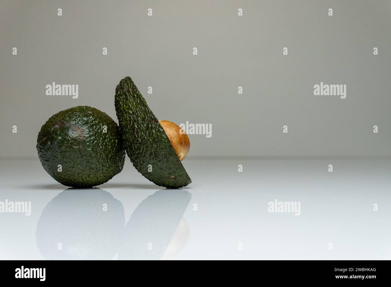 Foto accattivante con un avocado fresco collocato su un tavolo bianco in un ambiente minimalista, evidenziando il suo gusto vivace e sano Foto Stock