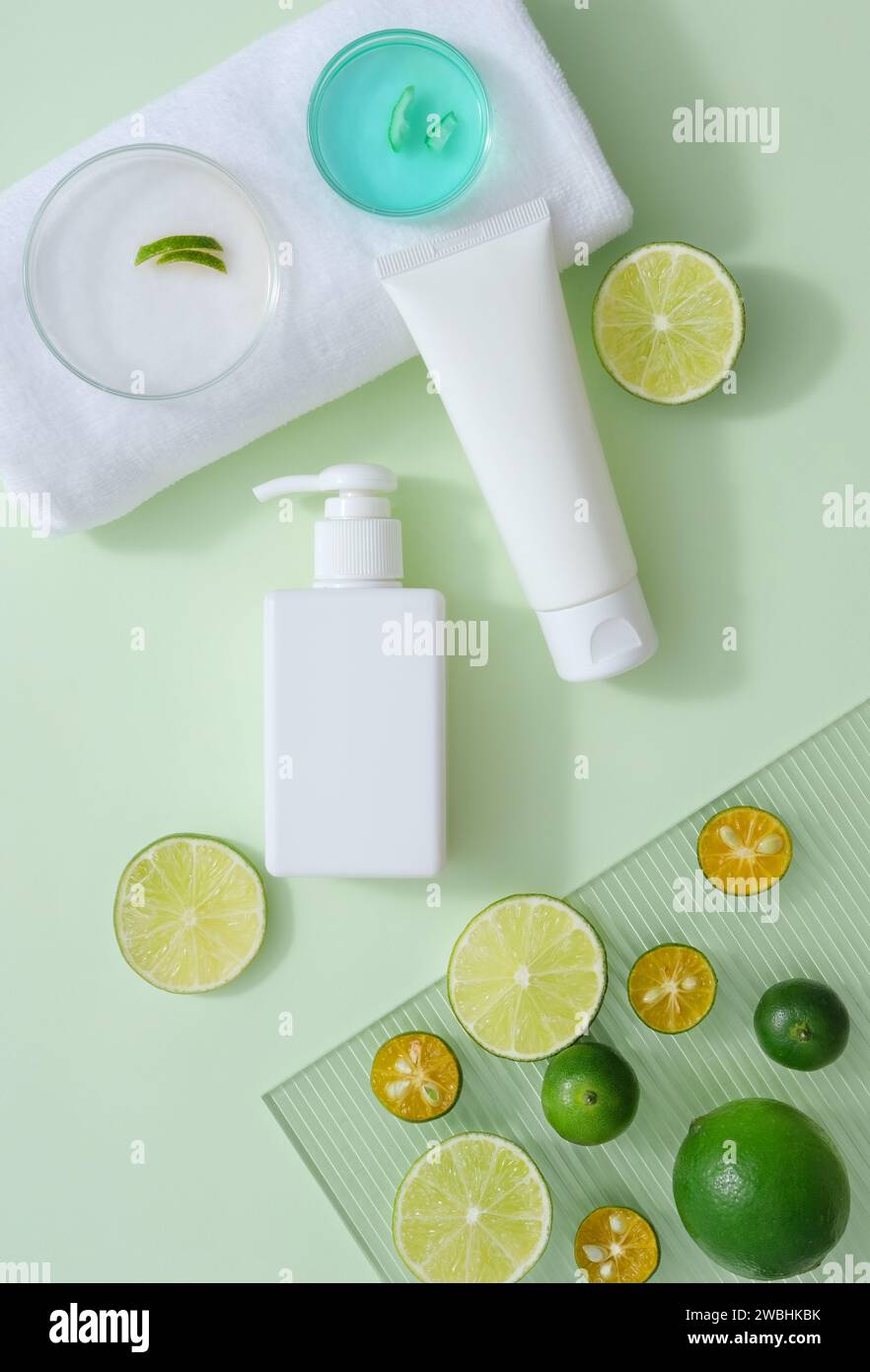 Piatti Petri di liquido blu e buccia messi su un asciugamano bianco. Contenitori cosmetici decorati con fette di kumquat e lime. Gli agrumi sono noti per loro Foto Stock