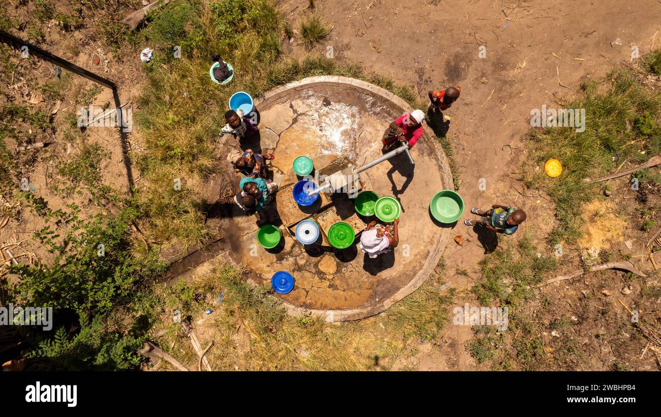 Un gruppo di individui si è riunito intorno a un pozzo nel villaggio di Quionga, Mozambico Foto Stock