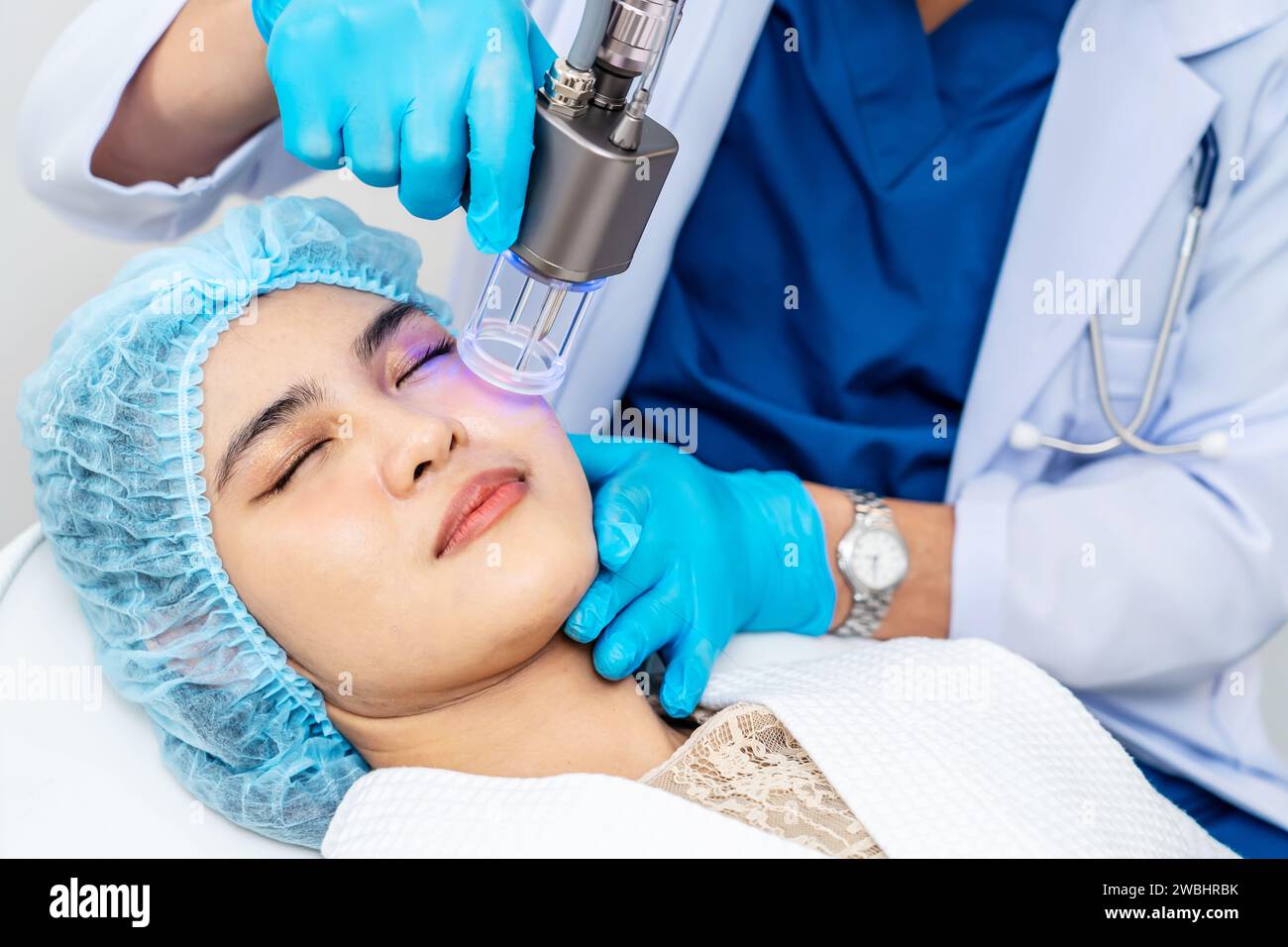Dottore asiatico che fa laser sulla faccia della donna alla clinica di bellezza. Bella donna con trattamento viso per la cura della pelle presso la clinica di bellezza, trattamento viso anti-invecchiamento Foto Stock